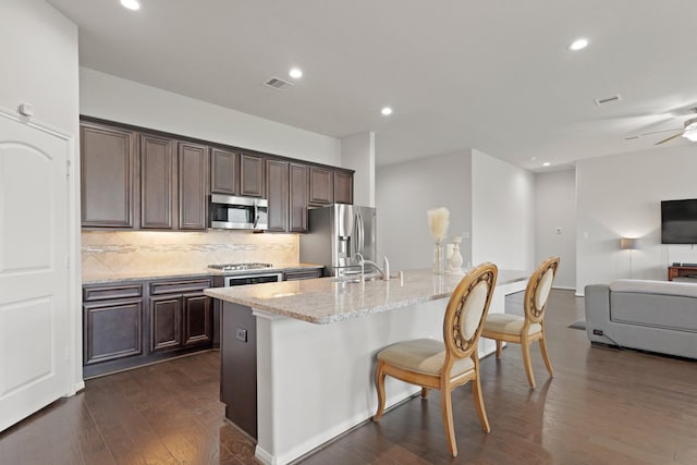 23522 Messina Harbor Dr, Katy, TX 77493 - kitchen with stainless steel appliances, a kitchen breakfast bar, dark brown cabinetry, dark wood-style floors, and recessed lighting