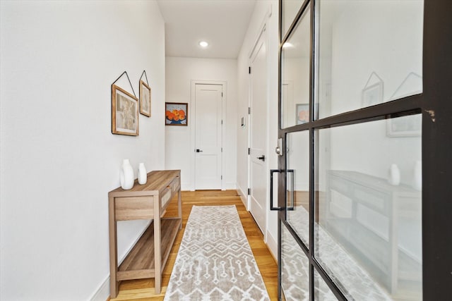 hall with light wood-style floors and baseboards