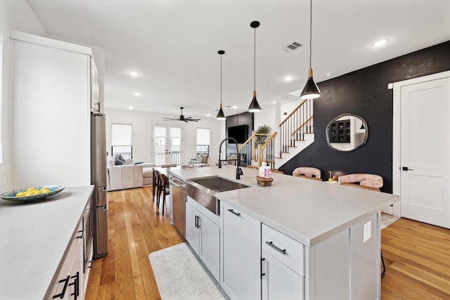 kitchen with a sink, open floor plan, ceiling fan, light wood finished floors, and recessed lighting