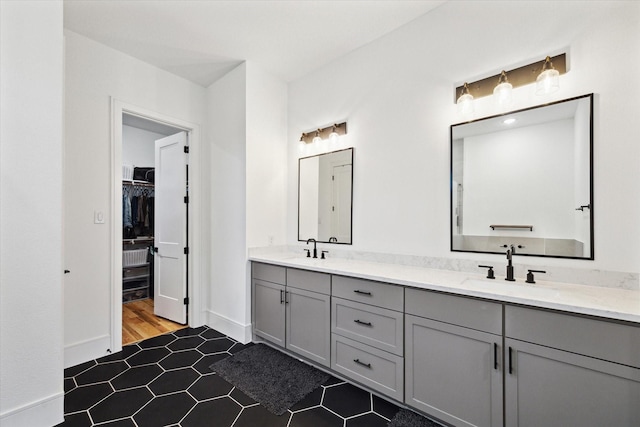bathroom featuring double vanity, a spacious closet, baseboards, and tile patterned floors