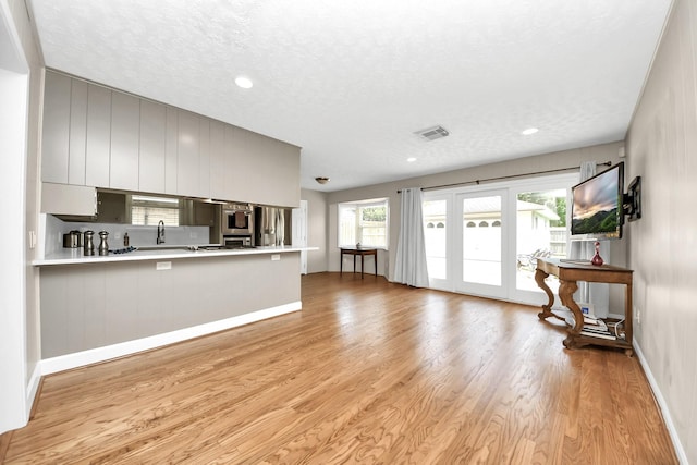 1815 Tannehill Dr, Houston, TX 77008 - unfurnished living room with light wood-style flooring, baseboards, recessed lighting, a textured ceiling, and french doors