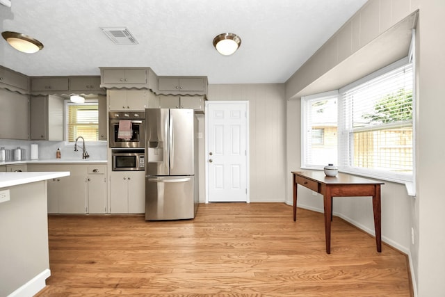 1815 Tannehill Dr, Houston, TX 77008 - kitchen with stainless steel refrigerator with ice dispenser, light countertops, light wood-style flooring, baseboards, and gray cabinets