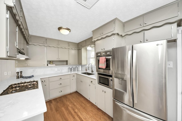 1815 Tannehill Dr, Houston, TX 77008 - kitchen featuring appliances with stainless steel finishes, a sink, light countertops, light wood finished floors, and under cabinet range hood