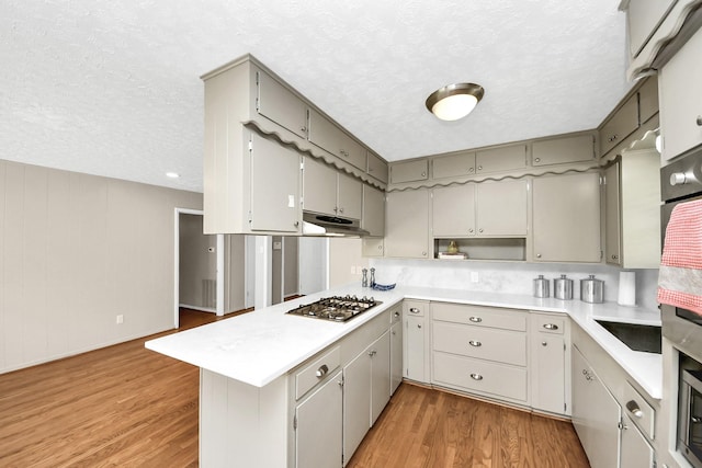 1815 Tannehill Dr, Houston, TX 77008 - kitchen with a peninsula, stainless steel gas cooktop, a textured ceiling, light countertops, and light wood-style flooring