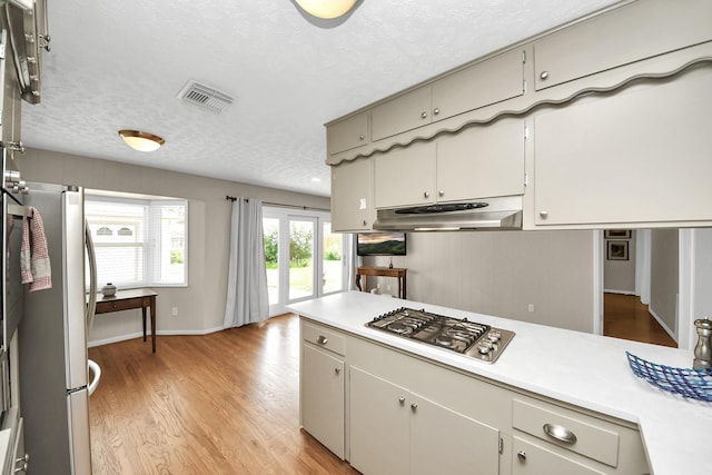 1815 Tannehill Dr, Houston, TX 77008 - kitchen featuring stainless steel appliances, under cabinet range hood, light countertops, a textured ceiling, and light wood finished floors
