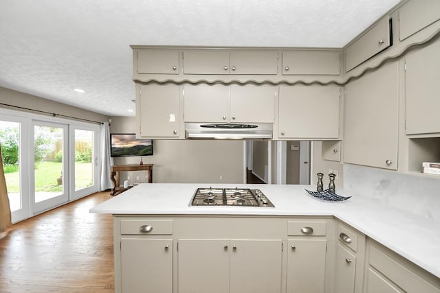 1815 Tannehill Dr, Houston, TX 77008 - kitchen featuring under cabinet range hood, stainless steel gas stovetop, a textured ceiling, light countertops, and a peninsula