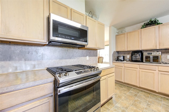 1414 Stevens Ct, Rosenberg, TX 77471 - kitchen with appliances with stainless steel finishes, light brown cabinetry, light countertops, and backsplash