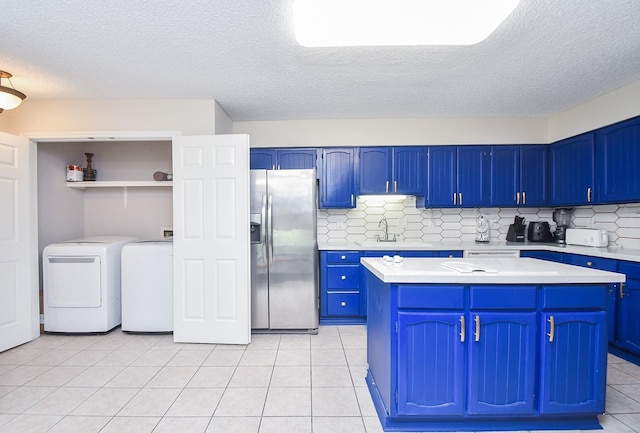 18143 Bal Harbour Dr, Houston, TX 77058 - kitchen featuring stainless steel fridge with ice dispenser, blue cabinetry, independent washer and dryer, light countertops, and a center island
