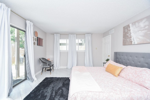 18143 Bal Harbour Dr, Houston, TX 77058 - bedroom with light tile patterned flooring, access to outside, a textured ceiling, and baseboards