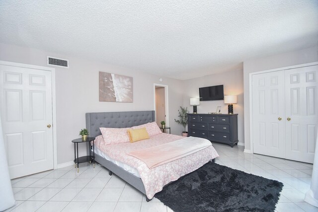 18143 Bal Harbour Dr, Houston, TX 77058 - bedroom with a textured ceiling, light tile patterned floors, a closet, and baseboards