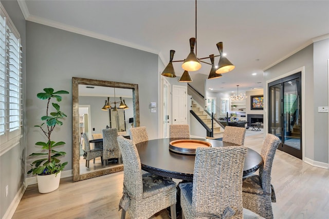 dining area featuring a chandelier, stairway, ornamental molding, light wood finished floors, and baseboards