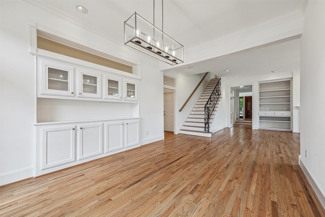 5302 Huisache St, Bellaire, TX 77401 - unfurnished living room featuring ornamental molding, light wood-style floors, a chandelier, stairway, and baseboards