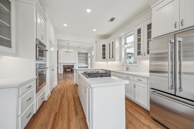 5302 Huisache St, Bellaire, TX 77401 - kitchen featuring stainless steel appliances, a sink, ornamental molding, a chandelier, and a center island