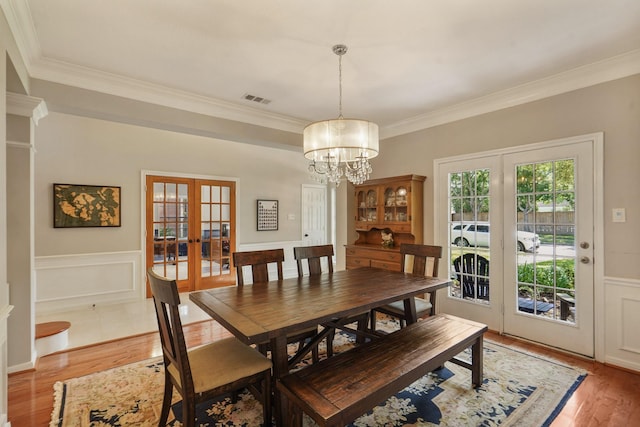 3303 Quiet Lake Dr, Katy, TX 77450 - dining space featuring french doors, light wood finished floors, crown molding, a chandelier, and a wainscoted wall