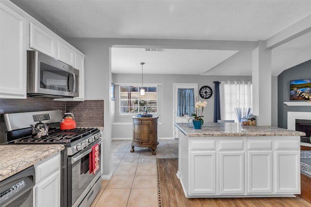 16222 Indian Cypress Dr, Cypress, TX 77429 - kitchen featuring appliances with stainless steel finishes, white cabinetry, tasteful backsplash, light wood-style floors, and pendant lighting