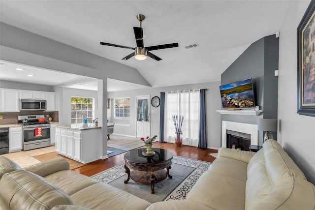 16222 Indian Cypress Dr, Cypress, TX 77429 - living area with light wood-type flooring, ceiling fan, vaulted ceiling, a fireplace, and baseboards