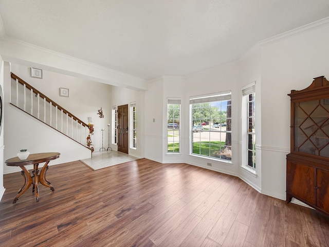 foyer entrance featuring wood finished floors, stairway, and ornamental molding