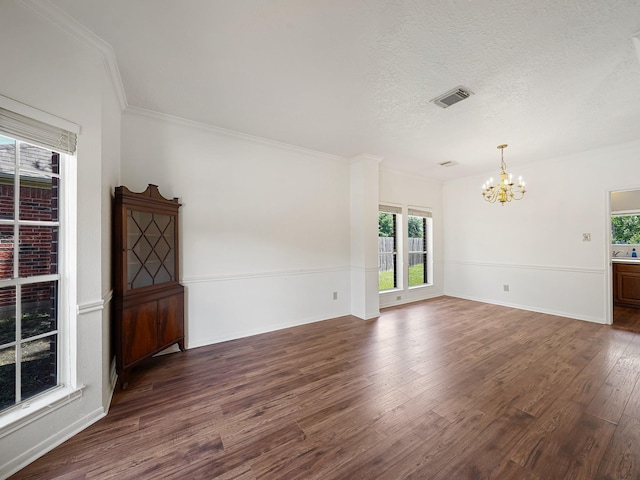 empty room featuring a chandelier, plenty of natural light, dark wood-style flooring, ornamental molding, and a textured ceiling