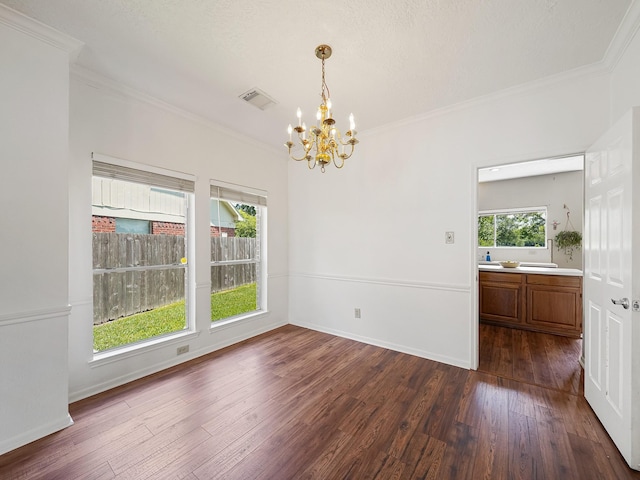 unfurnished dining area featuring a chandelier, crown molding, dark wood-style flooring, and baseboards