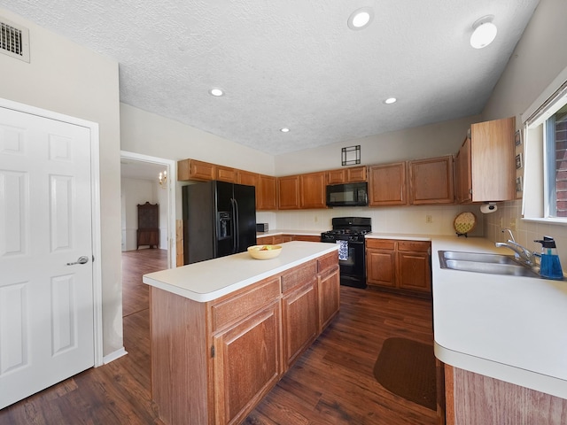 kitchen with black appliances, a sink, a kitchen island, light countertops, and dark wood-style floors