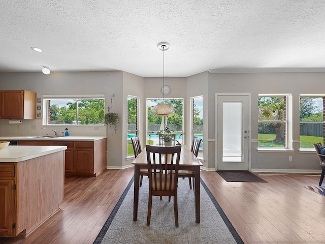 dining space featuring a textured ceiling, light wood-style floors, plenty of natural light, baseboards, and recessed lighting