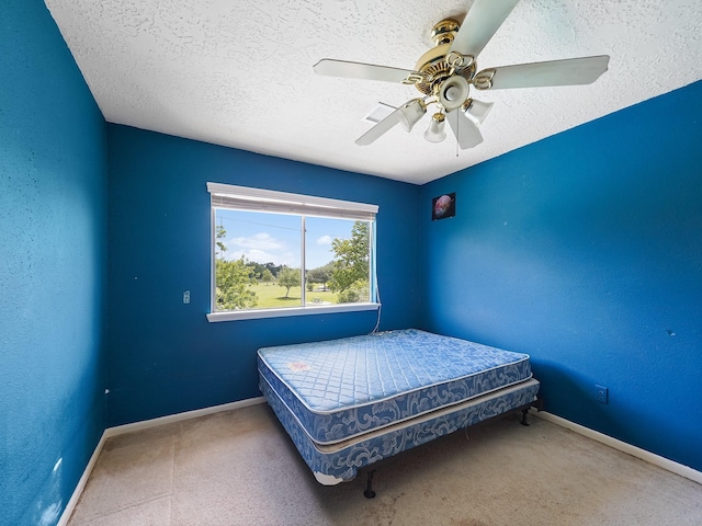 carpeted bedroom featuring baseboards, ceiling fan, and a textured ceiling