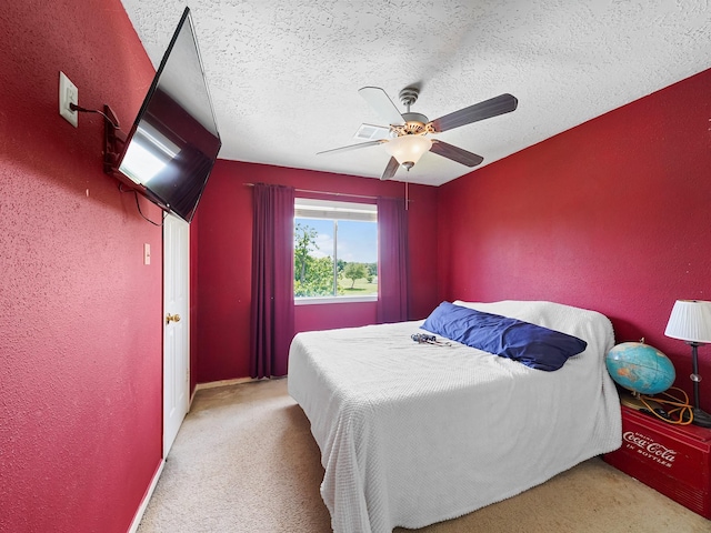 carpeted bedroom featuring a textured ceiling, a ceiling fan, and a textured wall