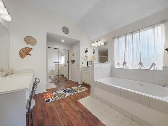 full bath with vaulted ceiling, wood finished floors, a bath, vanity, and a shower