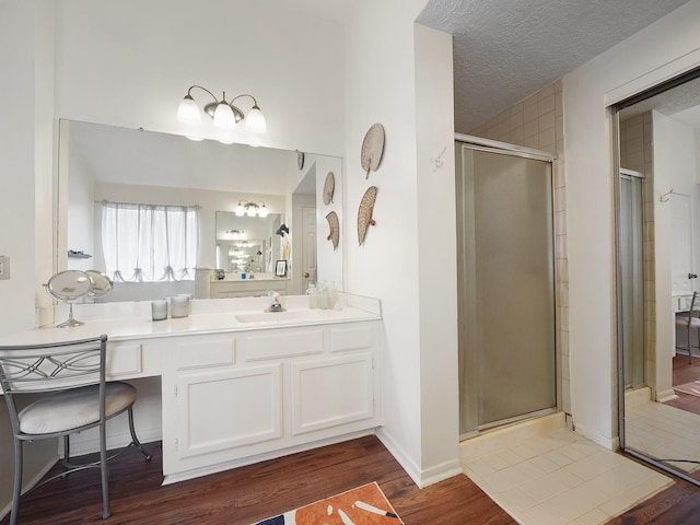 bathroom featuring a stall shower, wood finished floors, vanity, and a textured ceiling