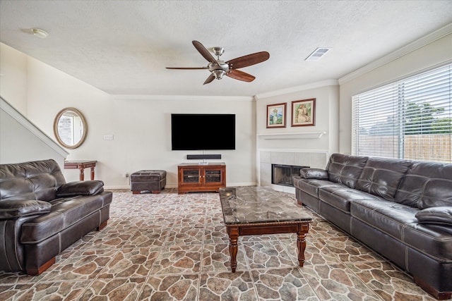 17022 Scuttle Way, Crosby, TX 77532 - living area with stone floors, a ceiling fan, a textured ceiling, ornamental molding, and a tile fireplace