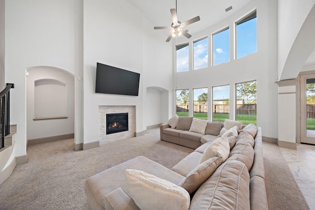 3306 Willow Fin Way, Richmond, TX 77406 - living room featuring a high ceiling, a stone fireplace, baseboards, a ceiling fan, and light carpet