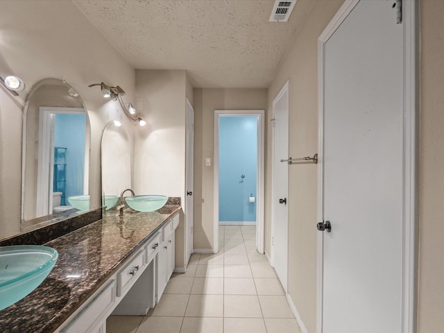 10218 Sagerock Dr, Houston, TX 77089 - full bath with toilet, tile patterned floors, double vanity, a textured ceiling, and baseboards