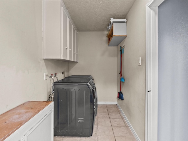 10218 Sagerock Dr, Houston, TX 77089 - clothes washing area featuring washer and dryer, light tile patterned floors, cabinet space, a textured ceiling, and baseboards