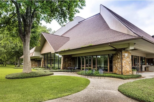 2019 Foxtail Creek Ct, Crosby, TX 77532 - rear view of property featuring stone siding, a lawn, a shingled roof, and a patio