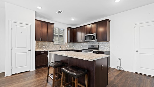 321 Lippizan Dr, Alvin, TX 77511 - kitchen with stainless steel appliances, decorative backsplash, dark wood finished floors, dark brown cabinetry, and recessed lighting