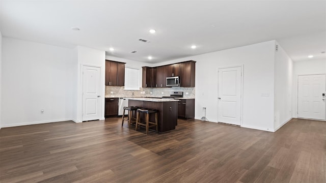 321 Lippizan Dr, Alvin, TX 77511 - kitchen featuring stainless steel appliances, a center island, dark brown cabinets, dark wood-type flooring, and tasteful backsplash