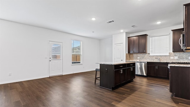 321 Lippizan Dr, Alvin, TX 77511 - kitchen featuring appliances with stainless steel finishes, a center island, a breakfast bar, dark wood-style floors, and tasteful backsplash