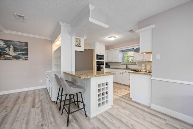 7906 Beaufort Dr, Spring, TX 77379 - kitchen with stainless steel appliances, a peninsula, a textured ceiling, white cabinetry, and light wood finished floors