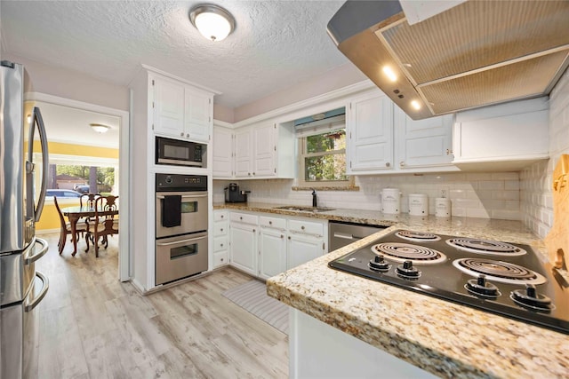 7906 Beaufort Dr, Spring, TX 77379 - kitchen with extractor fan, black appliances, white cabinetry, light wood finished floors, and a sink
