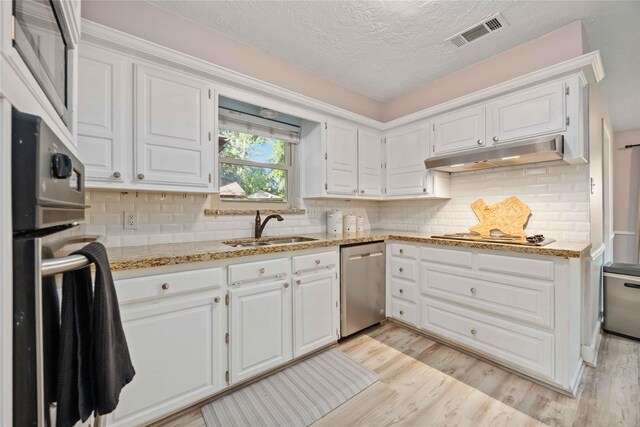 7906 Beaufort Dr, Spring, TX 77379 - kitchen featuring appliances with stainless steel finishes, under cabinet range hood, a sink, white cabinetry, and a textured ceiling