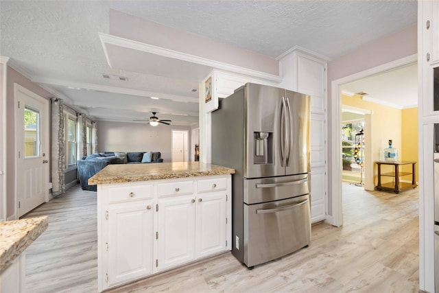 7906 Beaufort Dr, Spring, TX 77379 - kitchen with stainless steel fridge, light wood-style floors, white cabinetry, a textured ceiling, and a peninsula
