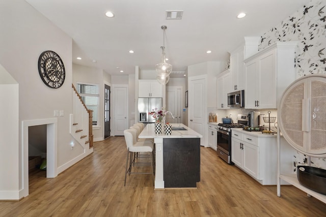kitchen featuring appliances with stainless steel finishes, a sink, a breakfast bar, white cabinetry, and recessed lighting