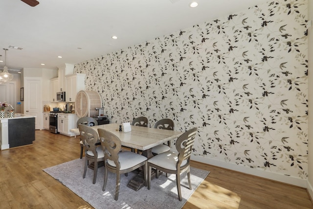 dining space featuring wallpapered walls, wood finished floors, baseboards, and recessed lighting