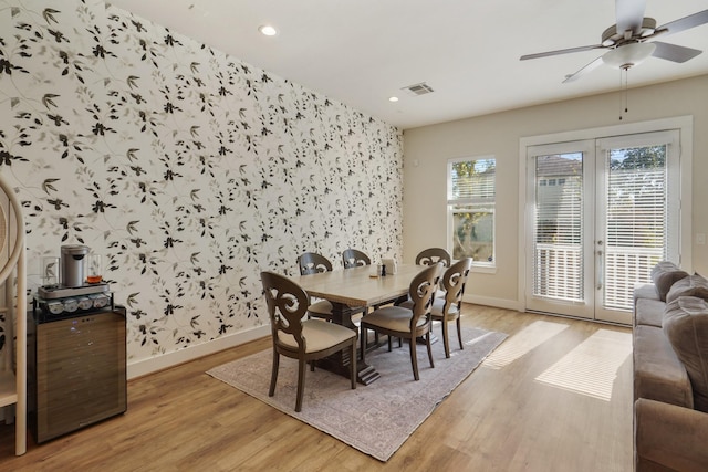 dining space with french doors, baseboards, light wood-style floors, wallpapered walls, and ceiling fan