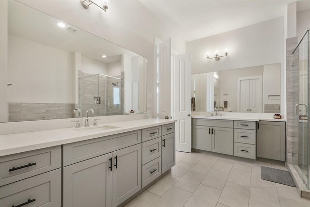 bathroom featuring tile patterned floors, a stall shower, and two vanities