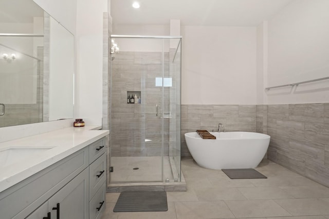 full bath featuring a stall shower, vanity, a freestanding tub, tile patterned flooring, and wainscoting