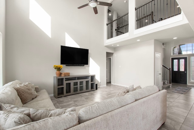 living room with stairway, a towering ceiling, ceiling fan, baseboards, and recessed lighting