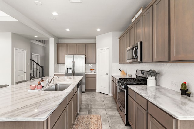 kitchen with appliances with stainless steel finishes, a sink, a large island, tasteful backsplash, and recessed lighting