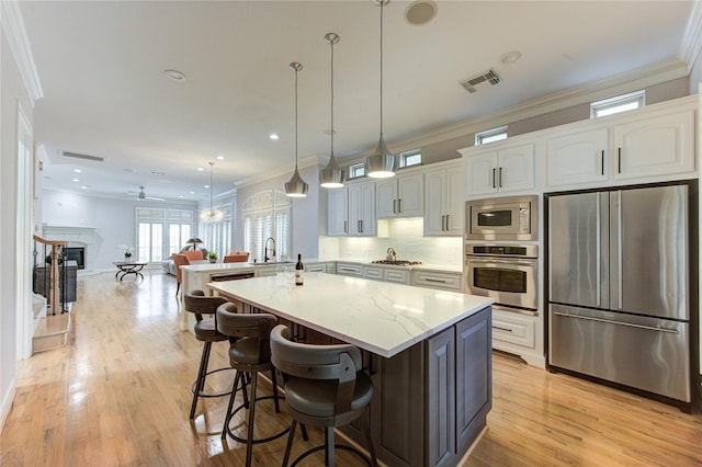 3331 Bingham Manor Ln, Houston, TX 77056 - kitchen with appliances with stainless steel finishes, crown molding, a sink, light wood finished floors, and white cabinetry