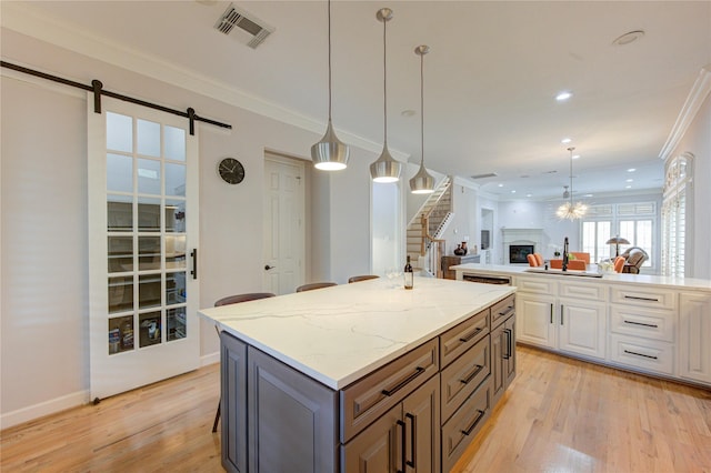 3331 Bingham Manor Ln, Houston, TX 77056 - kitchen featuring a fireplace, light wood-style flooring, a barn door, white cabinets, and open floor plan